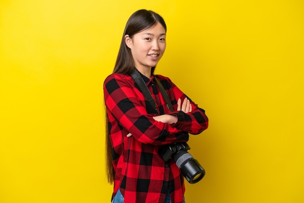 Jeune photographe femme chinoise isolée sur fond jaune avec les bras croisés et impatient