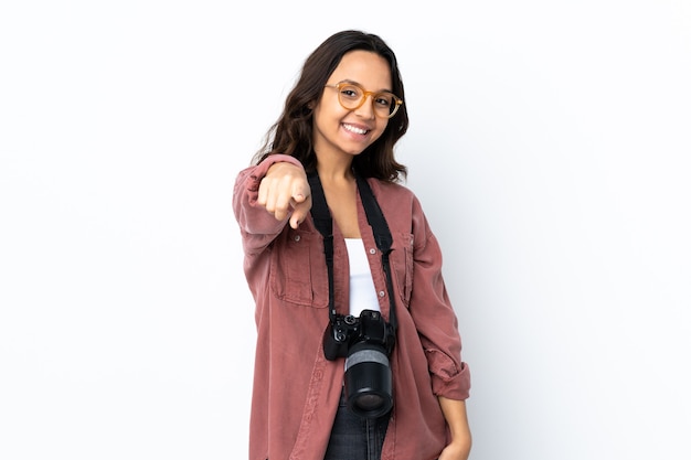 Jeune photographe femme sur fond blanc isolé pointant vers l'avant avec une expression heureuse