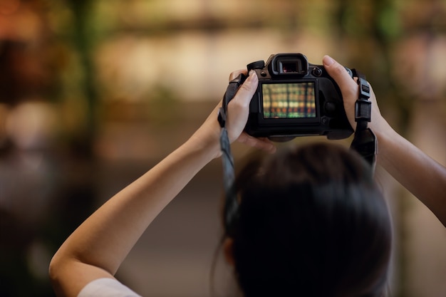 Jeune photographe femme soulève un appareil photo pour prendre une photo.