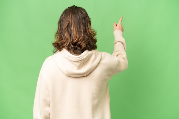 Jeune photographe homme sur fond isolé pointant vers l'arrière avec l'index