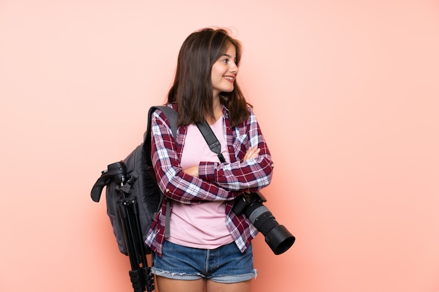 Jeune photographe sur mur rose isolé, regardant sur le côté