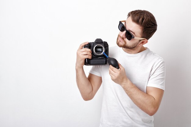 Jeune photographe nettoyage appareil photo avec pompe à vide. nettoyeur de poussière de souffleur à main pour appareil photo et objectifs.