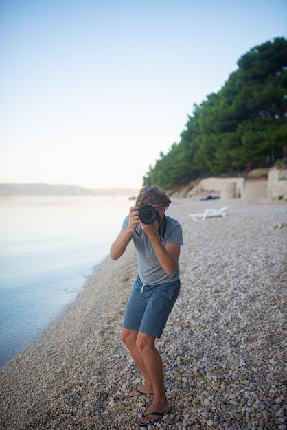 Jeune photographe à la plage prenant une photo sur vous