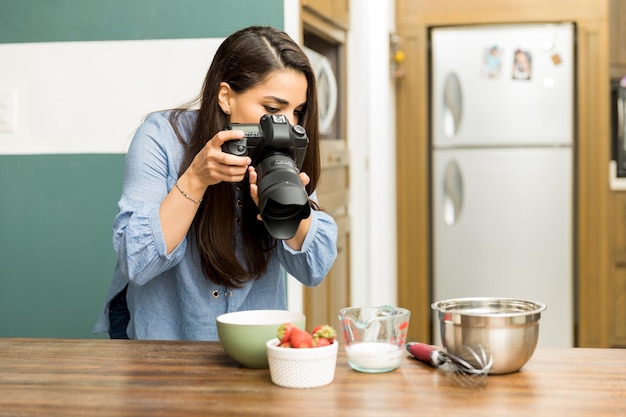 Jeune photographe professionnel prenant des photos de nourriture dans une cuisine