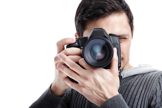 Jeune photographe professionnel réussi en chemise utilise un appareil photo numérique DSLR isolé sur fond blanc. fermer