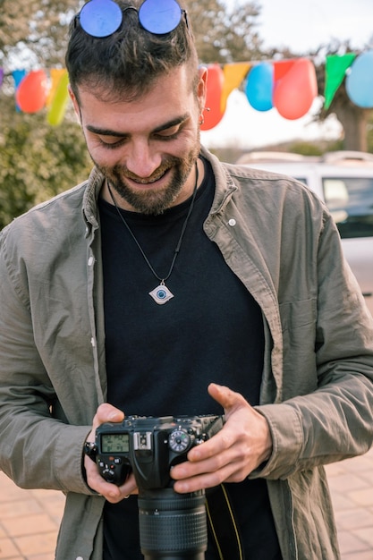 Un jeune photographe souriant en regardant les photos qu'il a prises avec son appareil photo lors d'une fête