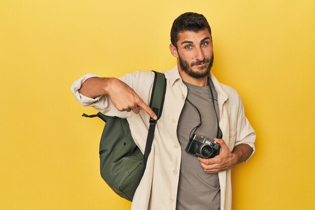 Photo un jeune photographe de voyage hispanique pose une personne pointant de la main vers un espace de copie de chemise