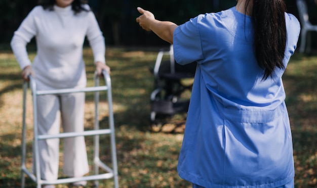 Jeune physiothérapeute asiatique travaillant avec une femme âgée sur la marche avec un déambulateur