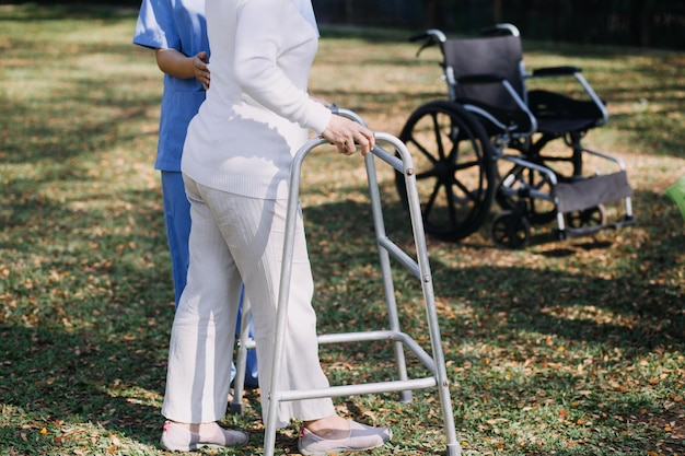 Jeune physiothérapeute asiatique travaillant avec une femme âgée sur la marche avec un déambulateur