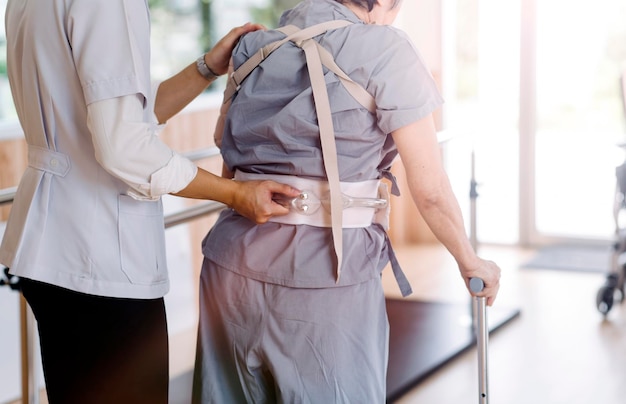 Jeune physiothérapeute asiatique travaillant avec une femme âgée sur la marche avec un déambulateur