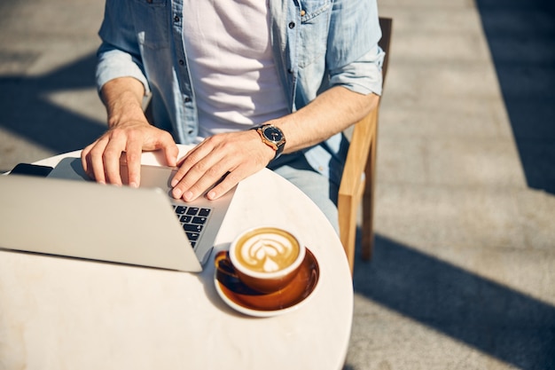 Jeune pigiste assis à la table et se tenant la main sur le clavier, travaillant sur son projet