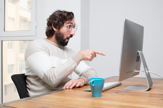 Jeune pigiste fou barbu travaillant avec son ordinateur