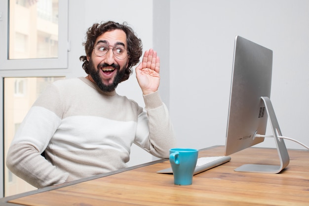 Jeune pigiste fou barbu travaillant avec son ordinateur