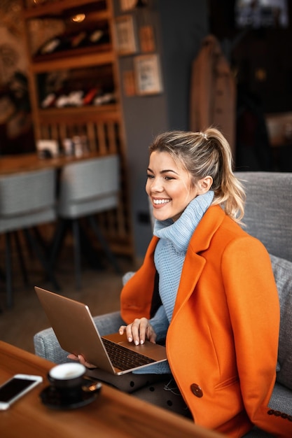 Jeune pigiste heureux surfant sur le net sur un ordinateur pendant une pause-café à la cafétéria