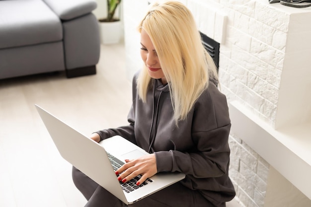 Une jeune pigiste positive et réussie travaille sur un ordinateur portable. Travaillez depuis l'appartement à distance en ligne. Atmosphère confortable du bureau à domicile. programmeur web d'entreprise concepteur développeur