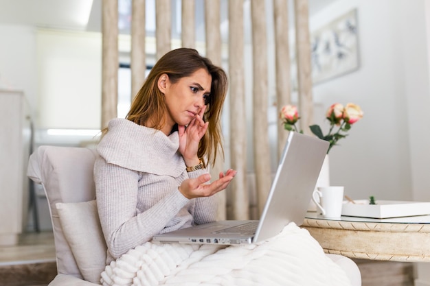 Jeune pigiste stressé assis et travaillant sur un ordinateur portable, regardant l'écran avec un visage inquiet. concept d'entreprise et de travail indépendant. Designer femme assise devant un ordinateur portable à la maison.