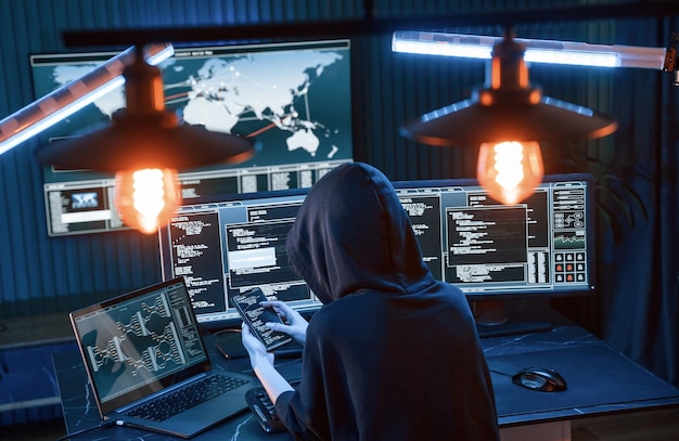 Une jeune pirate professionnelle est à l'intérieur d'un ordinateur avec beaucoup d'informations sur les écrans