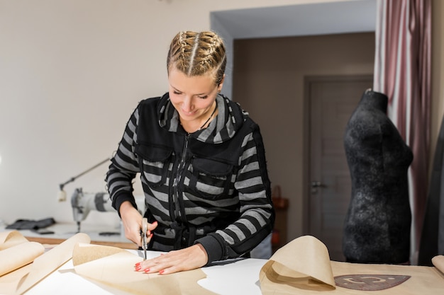 Jeune pochoir souriant de ciseaux de tailleur pour confectionner des vêtements