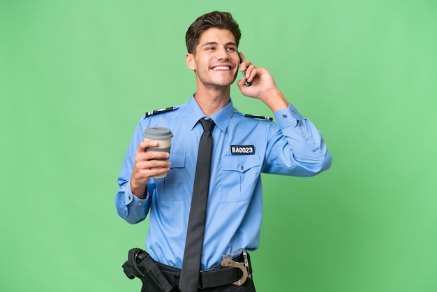 Jeune policier sur fond isolé tenant du café à emporter et un mobile