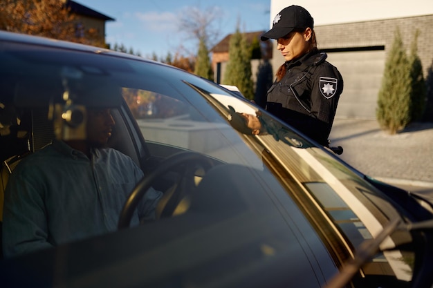 Jeune policière avec tablette debout près de la voiture