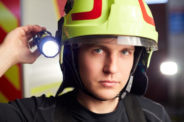 Jeune pompier en uniforme debout devant un camion de pompiers, il est prêt à être déployé