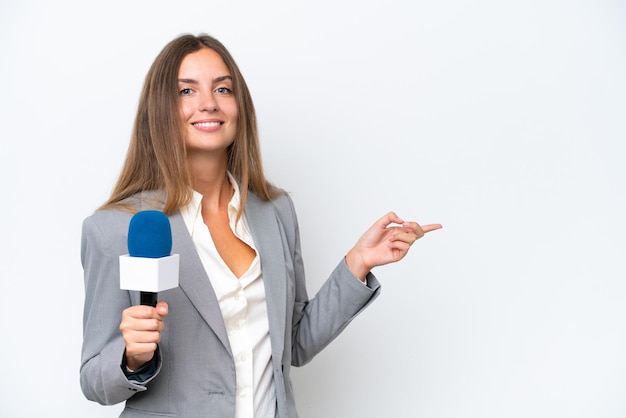 Jeune présentatrice de télévision femme caucasienne isolée sur fond blanc pointant le doigt sur le côté