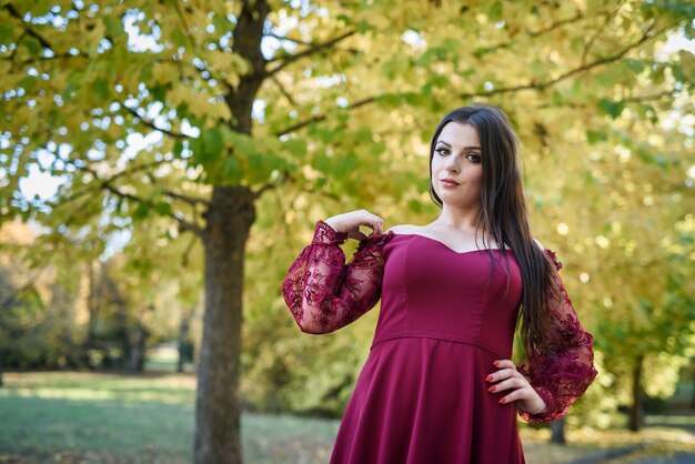 Jeune princesse dans une belle robe rouge dans le parc. L'arrière-plan est une nature d'automne brillante et dorée.