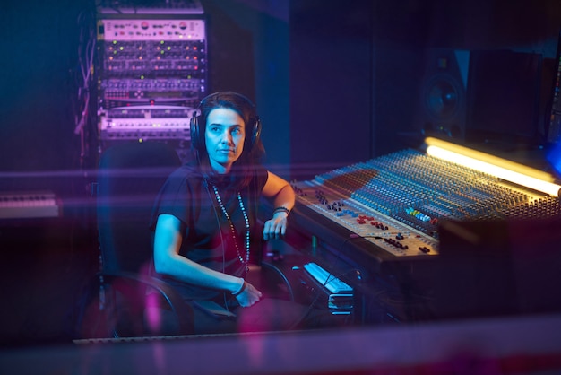 Jeune producteur de musique au casque assis au clavier musical et écrivant des chansons en studio