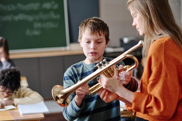 Un jeune professeur de musique donne une trompette à un élève.