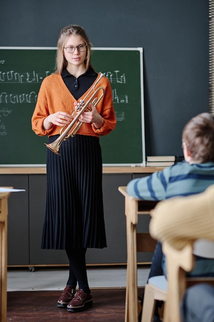 Un jeune professeur de musique tient une trompette pour diriger une leçon.