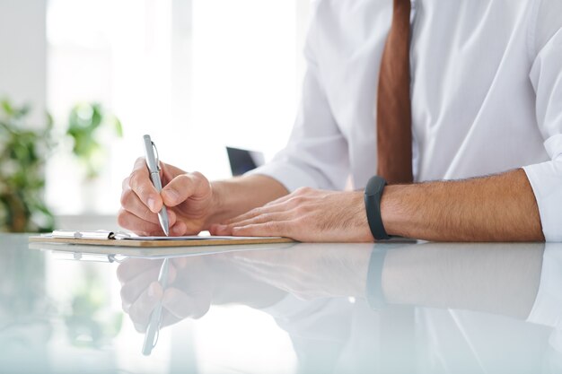 Jeune professionnel inspiré avec un stylo pour prendre des notes ou dessiner au bureau pendant le travail