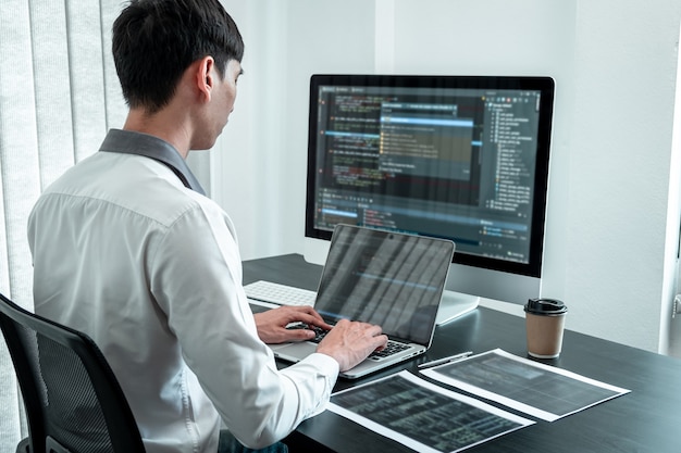Jeune programmeur travaillant dans un ordinateur javascript logiciel dans un bureau informatique, écrivant des codes et un site Web de code de données et des technologies de base de données de codage pour trouver une solution au problème.