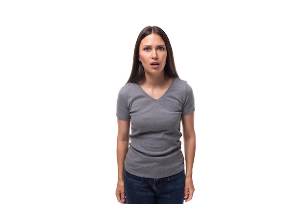 Jeune promotrice brune surprise vêtue d'un t-shirt gris sur fond blanc