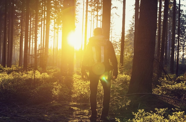 Jeune randonneur appréciant les visages du coucher du soleil dans les bois