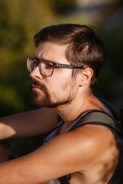 Jeune randonneur avec sac à dos relaxant au sommet d'une montagne pendant le calme coucher de soleil d'été