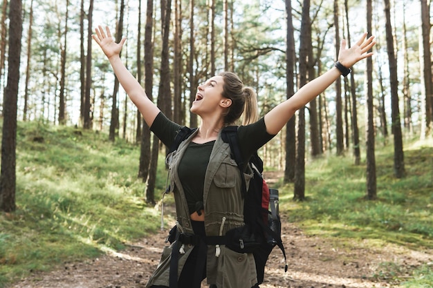 Jeune randonneuse avec grand sac à dos dans la forêt verte