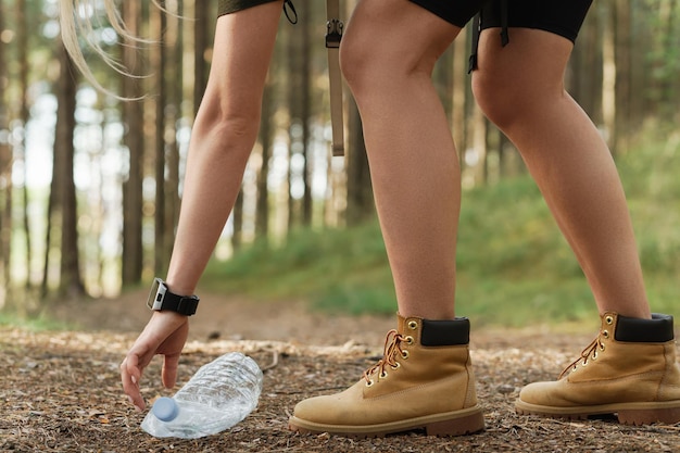 Jeune randonneuse ramassant des déchets plastiques dans la forêt verte