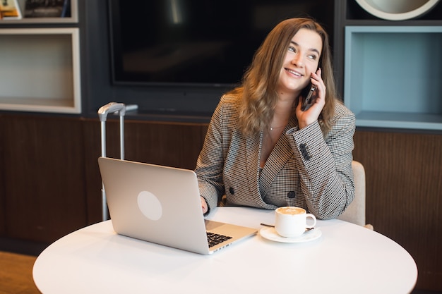 Jeune rédactrice créant un texte pour publier des articles sur un site Web de contenu à l'aide d'un netbook tout en travaillant à distance à l'intérieur.