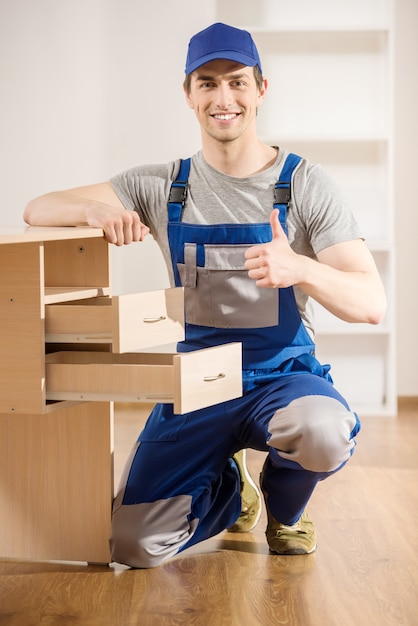 Jeune réparateur en train d'assembler une nouvelle table à l'intérieur de la maison.