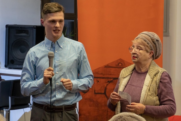 Un jeune reporter tenant un micro Conversation avec un vieil homme sur scène Le retraité raconte une histoire Discours d'un ancien combattant au festival