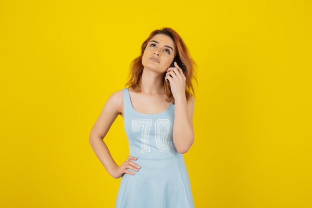 Jeune rousse réfléchie sur jaune en levant.