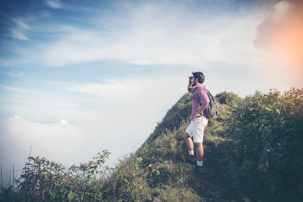 jeune routard mâle profiter de la vue au sommet de la montagne