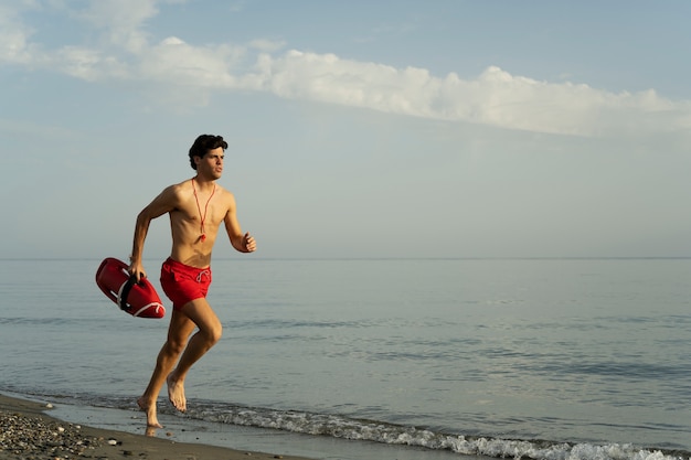 Photo jeune sauveteur s'exécutant sur la plage plein coup