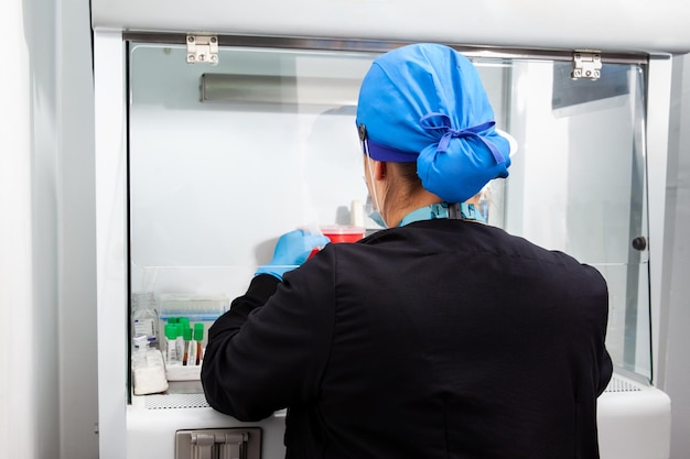 Une jeune scientifique travaille dans une armoire de sécurité à flux d'air laminaire au laboratoire.