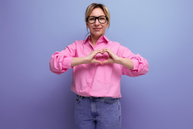 Jeune secrétaire blonde caucasienne énergique avec des lunettes de coiffure en queue de cheval et dans une chemise rose