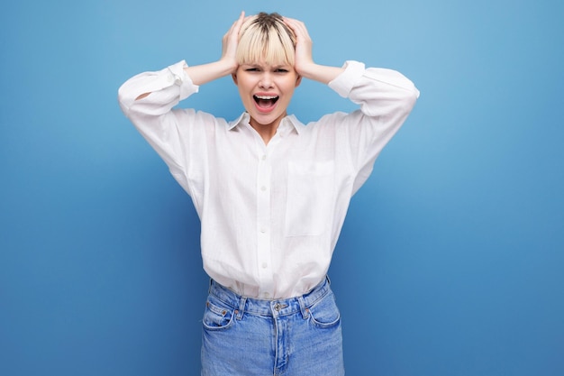 Jeune secrétaire jolie blonde émotionnelle vêtue d'une chemise blanche sur fond bleu avec copie