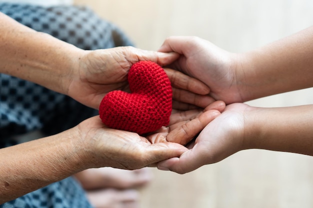 Jeune et senior femme se tenant la main et le concept de convivialité en forme de coeur de fil rouge