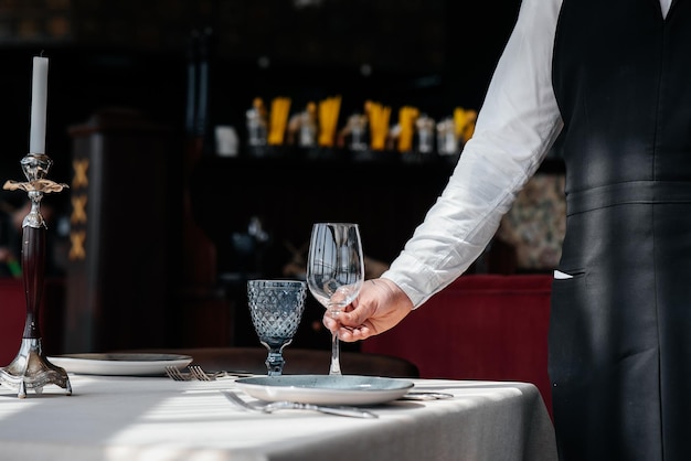 Un jeune serveur dans un uniforme élégant est engagé dans le service de la table dans un beau restaurant gastronomique en gros plan Service de table dans le restaurant
