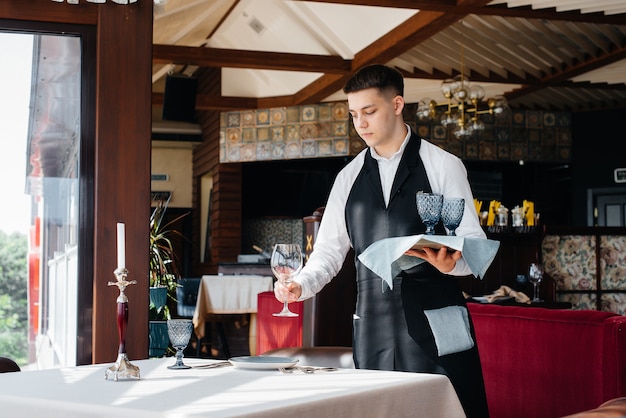 Un jeune serveur masculin dans un uniforme élégant est occupé à servir la table dans un beau restaurant gastronomique. Activité de restauration, du plus haut niveau.