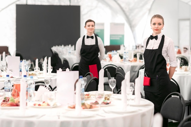 Jeune serveuse debout dans la salle de banquet du restaurant